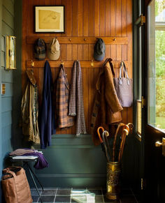 a coat rack with hats and umbrellas hanging from it's sides next to a window