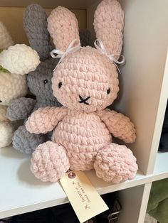 there is a crocheted bunny sitting on the shelf next to other stuffed animals