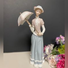 a figurine is holding an umbrella and standing on a table next to flowers