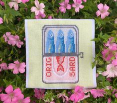 a cross stitch picture with three blue birds in a cage on top of pink flowers