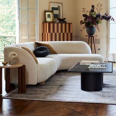 a living room filled with furniture and a vase on top of a table in front of a window