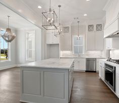 a kitchen with white cabinets and an island in the middle is lit by chandeliers