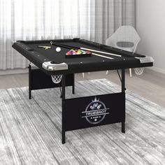 a black table with pool balls and cues on it in front of a white chair