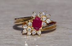 The Carboor: Natural Ruby and Diamond Ring in Yellow Gold. The ring centers on an oval brilliant cut natural ruby with a charming red color with glowing red fluorescence indicating its likely of Burma origin. The ruby has an approximate total weight by measurement of 0.44 carats. To the North-East and South-West of the center are round brilliant cut natural diamonds with an approximate total weight of 0.30 carats. The ring is crafted in 14 karat yellow gold and is currently a finger size 6 3/4 y Lily Ring, Ruby And Diamond Ring, Gold Sign, Gold Velvet, Ring Pictures, Red Band, South West, Natural Ruby, North East