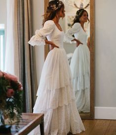 a woman is standing in front of a mirror wearing a dress with ruffles