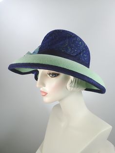 You'll look great in this pretty green and navy wool felt hat! It can easily transition from Winter to early Spring and is perfect for any dressy occasion. Imagine walking into church with this beauty! The flattering asymmetrical wide brim hat had a slight turned down brim with a cut out on the right side. It's topped with a gorgeous, extra wide ombre navy and green five loop bow that has a gorgeous Czech glass button in the center. This hat that will be the envy of everyone who sees it! The top Green Felt Hat With Curved Brim For Summer, Summer Green Felt Hat With Curved Brim, Green Summer Felt Hat With Curved Brim, Fitted Green Fedora For Kentucky Derby, Wool Brimmed Party Hat, Wool Party Hat With Short Brim, Wool Brimmed Hat For Party, Green Fitted Felt Hat With Flat Brim, Fitted Green Brimmed Fedora