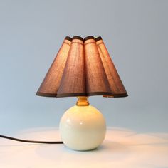 a lamp that is sitting on top of a white ball with a brown shade over it