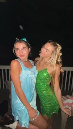 two beautiful young women standing next to each other in front of a balcony at night