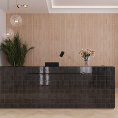 a black tiled reception counter with flowers in vases on the top and two lights hanging from the ceiling