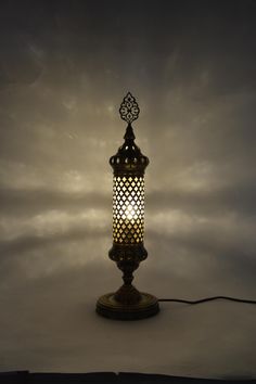 a lamp that is sitting on top of a wooden stand with a white light in the middle