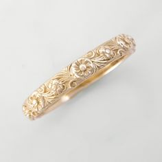 a gold ring with filigrees and flowers on the inside, sitting on a white surface