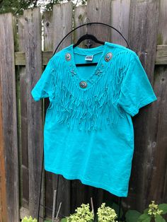 Super cool western shirt with FRINGE, SILVER and TURQUOISE detail.  Such a cool tee Made in USA. Blue Western Tops For Rodeo, Retro Tops For Western-themed Summer Events, Retro Summer Tops For Western-themed Events, Vintage T-shirt For Western-themed Summer Events, Vintage Short Sleeve Tops For Western-themed Events, Western Style Tops For Summer Western-themed Events, Western Style Tops For Summer Western Events, Casual Turquoise Tops For Festivals, Vintage Blue Tops For Rodeo