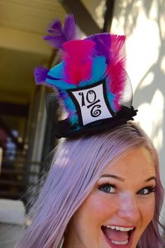 a woman with purple hair wearing a hat with feathers on it's head and the number twenty nine