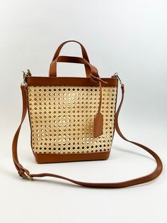 Stylish and perfect for the season, this woven rattan bag is the cutest accessory for all your summer outings! Product Details Material: Vegan Leather & Rattan Size: 10"L x11"W 5" Handle Drop Comes with side hooks to attach a longer shoulder strap One crossbody strap included Summer Woven Leather Top Handle Bag, Spring Handwoven Brown Shoulder Bag, Spring Brown Handwoven Shoulder Bag, Chic Rattan Bags With Woven Leather, Brown Woven Leather Straw Bag For Shopping, Leather Bucket Bag With Bamboo Handle For Beach, Leather Bucket Bag With Bamboo Handle For Vacation, Shopping Shoulder Bag In Woven Leather And Straw, Spring Top Handle Woven Leather Straw Bag