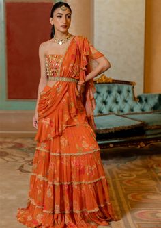 Featuring the rust pre-draped chiffon sari in our signature print , paired with kowri shell and coin detailed corset blouse. It is styled with our signature cutdana belt. Floral Ruffle Saree, Orange Saree Look, Mehendi Dresses, Blouse Corset, Ruffled Saree, Scallop Embroidery, Pleated Saree, Mehendi Outfit, Haldi Outfit