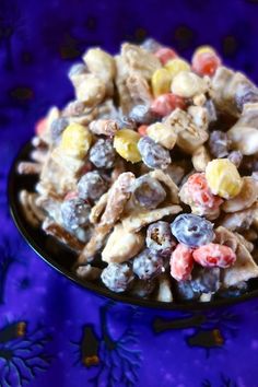 a bowl filled with candy corn salad on top of a purple table cloth next to blue flowers