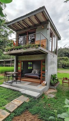 a small house with an open floor plan in the middle of grass and trees around it