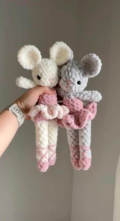 two crocheted stuffed animals are held in the air by someone's hand