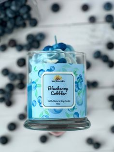 a blueberry cobbler candle is being held by someone