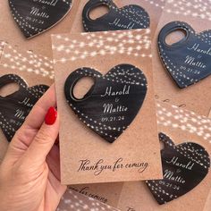 a person holding up some small wooden heart shaped magnets with wedding date on them