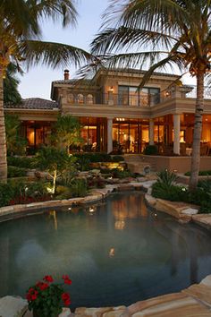 a house with a pool in front of it and palm trees around the pool area