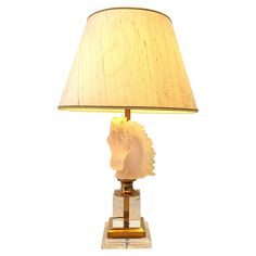 a table lamp with a gold base and a light shade on it's face