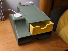 a yellow and green box sitting on top of a wooden table next to a bed