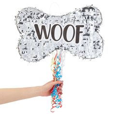 a hand holding a dog bone shaped balloon with the word woof written on it