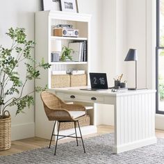 a white desk and chair in front of a book shelf with books on it next to a potted plant