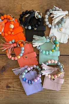 several purses are arranged on a wooden surface with beads and tassels hanging from them