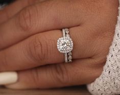 a close up of a person's hand with a diamond ring on their finger