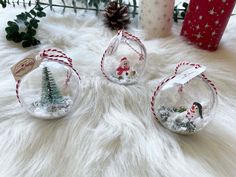 three glass christmas ornaments sitting on top of a white fur covered floor