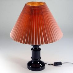 an orange lamp with a cord attached to it on a white tableclothed surface