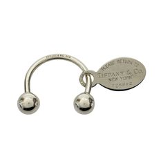 a metal hook with two balls hanging from it's end and a tag that says, please return to liberty & new york