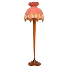 a wooden floor lamp with a pink shade on it's top and bottom half