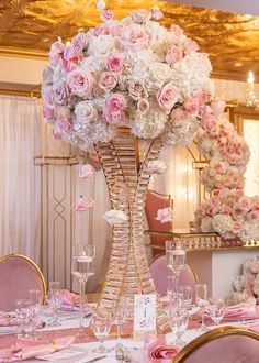 a tall vase filled with lots of pink and white flowers sitting on top of a table