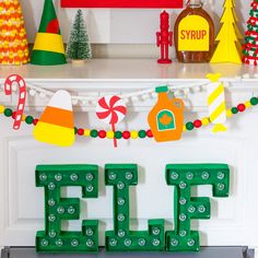 the word elf spelled out in front of christmas decorations on a mantel with candy canes and candies