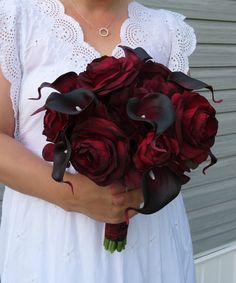 a woman holding a bouquet of red roses and calla lilies in her hands