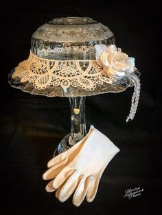 a hat and gloves are sitting on top of a glass stand with a white glove next to it