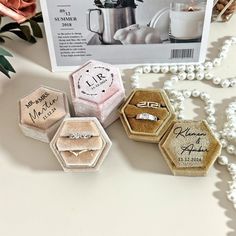 three wedding rings are on display next to some pearls and flowers with a magazine in the background