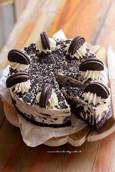 a cake with oreo cookies and cream on it sitting on top of a wooden table