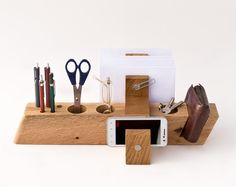 a cell phone and some office supplies on a wooden holder with magnets, pens, pencils, scissors and paper clips