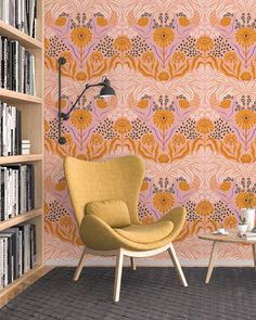 an orange chair sitting in front of a book shelf next to a table with a vase on it