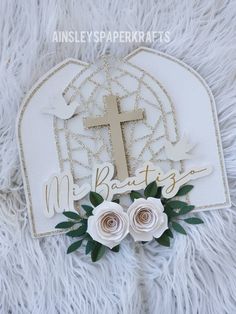 a cross and some flowers on top of a white furnishing area with the words miss betty written in gold