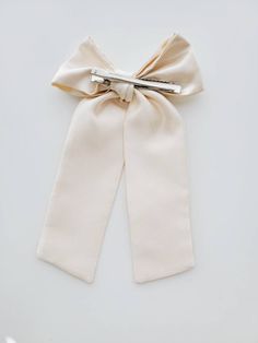 Finish: Alligator Clip * 9 inches long * Material: Satin Elegant Cream Bow For Parties, Elegant Cream Bow For Party, Elegant Cream Bow With Ribbon Detail, Elegant Cream Bow With Ribbon, Cream Ribbon Wedding Bow, Cream Satin Bow For Wedding, Elegant Cream Satin Bow, Bow With Pearls, Beaded Bow