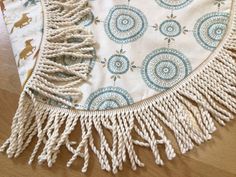 a white and blue table cloth with fringes on it sitting on top of a wooden floor