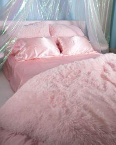 a bed with pink sheets and pillows in a room