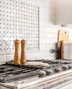 a kitchen stove with two pepper mill shakers on it's burners and a cutting board in the background