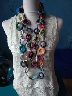 a woman wearing a white top with multicolored beads on it's neck