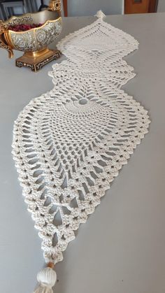 the table is covered with white crocheted doily and has a bowl on it